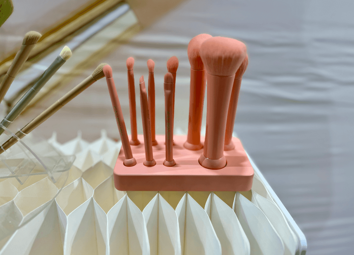 Set of pink makeup brushes in a stand on a decorative surface.